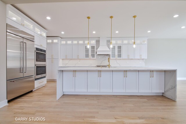 kitchen featuring white cabinets, stainless steel appliances, light wood-style floors, and custom range hood