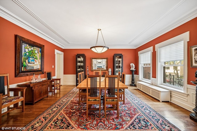 dining room featuring wainscoting, radiator, ornamental molding, and wood finished floors
