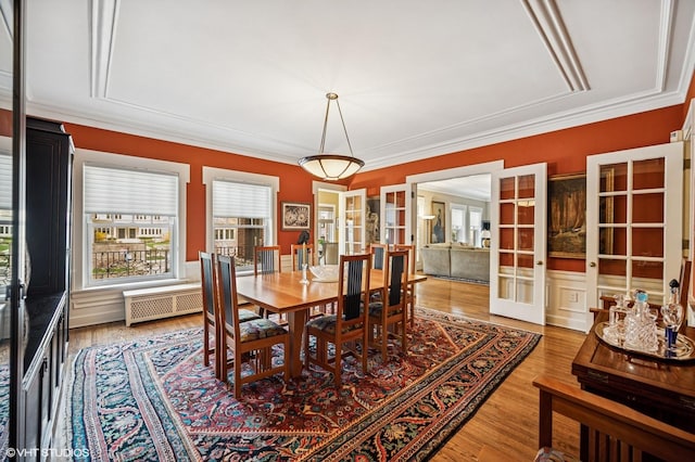 dining room featuring radiator, ornamental molding, french doors, and light wood-style floors
