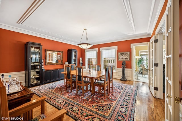 dining space featuring ornamental molding, a wainscoted wall, light wood-style floors, and french doors