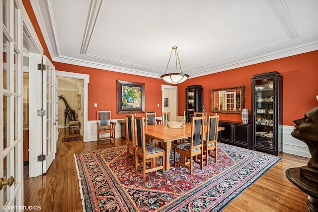 dining room with ornamental molding, french doors, wainscoting, and wood finished floors
