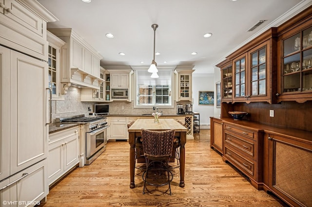 kitchen featuring a sink, stainless steel appliances, tasteful backsplash, crown molding, and light wood-type flooring