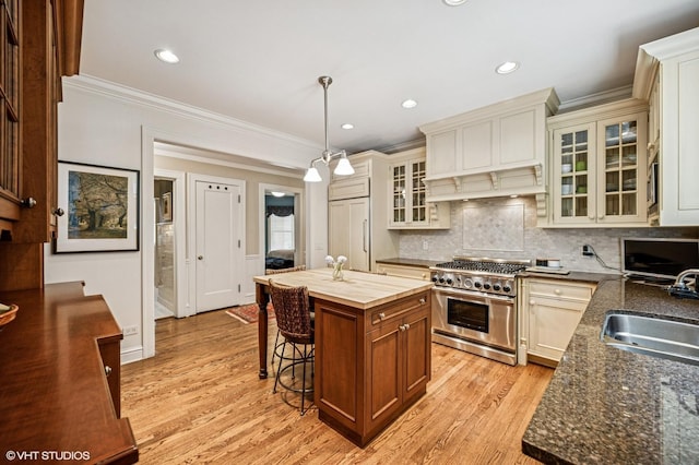 kitchen featuring ornamental molding, a kitchen bar, a sink, and high end appliances