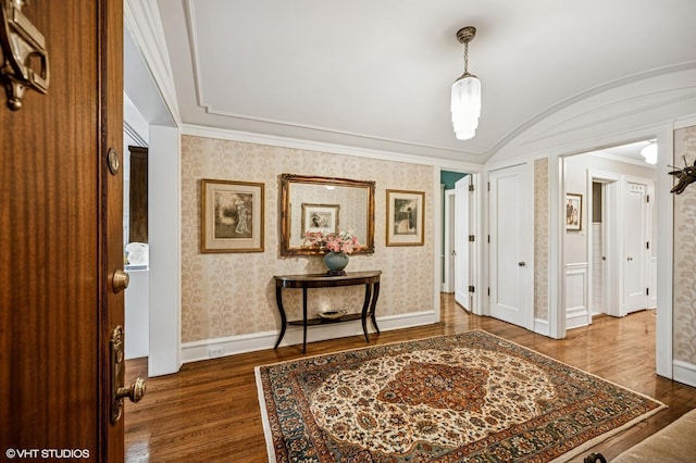 entryway with wood finished floors, wallpapered walls, vaulted ceiling, baseboards, and crown molding
