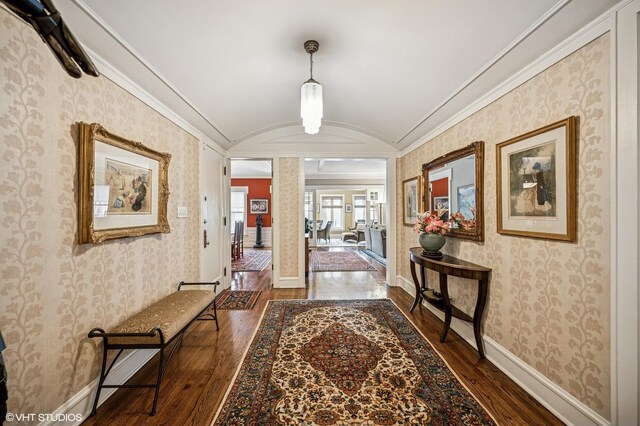 corridor featuring lofted ceiling, baseboards, crown molding, and wood-type flooring