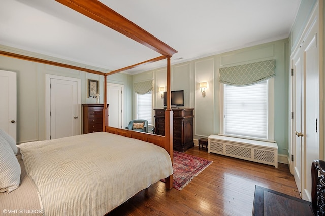 bedroom featuring wood finished floors, crown molding, and a decorative wall