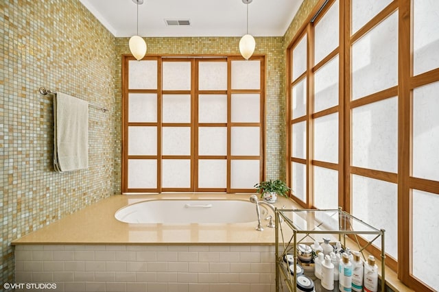 full bath featuring visible vents, a bath, and tile walls