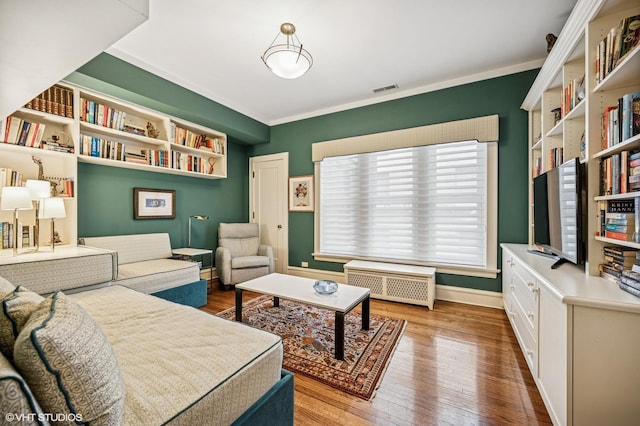 interior space featuring visible vents, radiator heating unit, wood finished floors, and crown molding