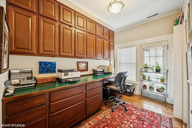 office featuring crown molding, built in study area, wood finished floors, and visible vents
