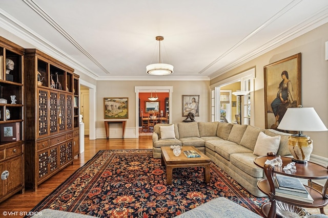 living room featuring wood finished floors, crown molding, and baseboards