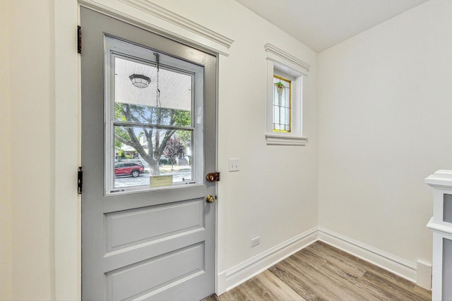 doorway with baseboards, wood finished floors, and plenty of natural light