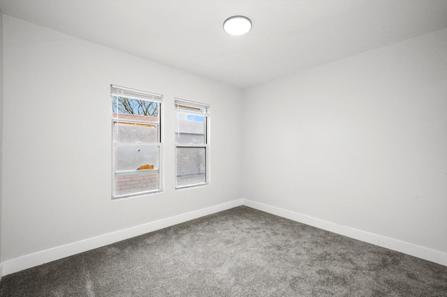 empty room featuring baseboards and dark carpet
