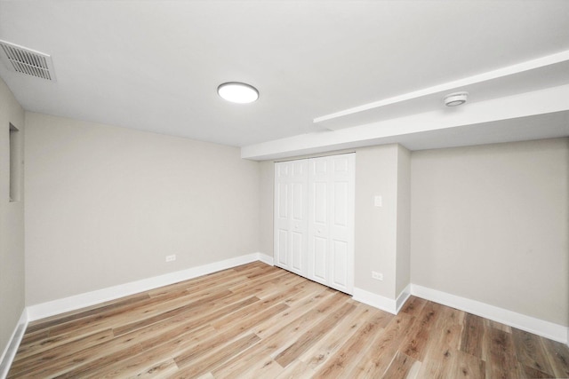 unfurnished bedroom featuring baseboards, wood finished floors, visible vents, and a closet
