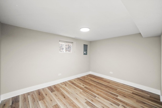 below grade area featuring baseboards, electric panel, and wood finished floors