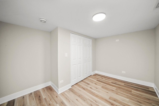unfurnished bedroom featuring a closet, light wood finished floors, baseboards, and visible vents