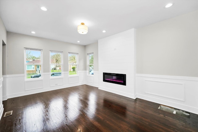 unfurnished living room featuring visible vents, wainscoting, wood finished floors, a fireplace, and recessed lighting