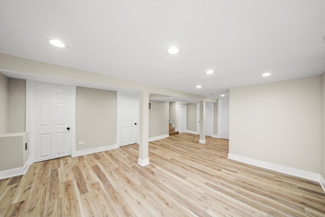 finished basement with stairway, baseboards, light wood finished floors, and recessed lighting