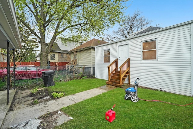 rear view of house with a lawn, fence, and entry steps