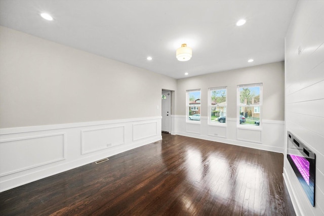 spare room with recessed lighting, dark wood-style flooring, and a wainscoted wall