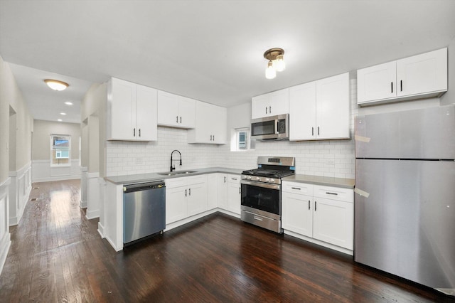 kitchen with dark wood-style flooring, white cabinetry, tasteful backsplash, a sink, and appliances with stainless steel finishes