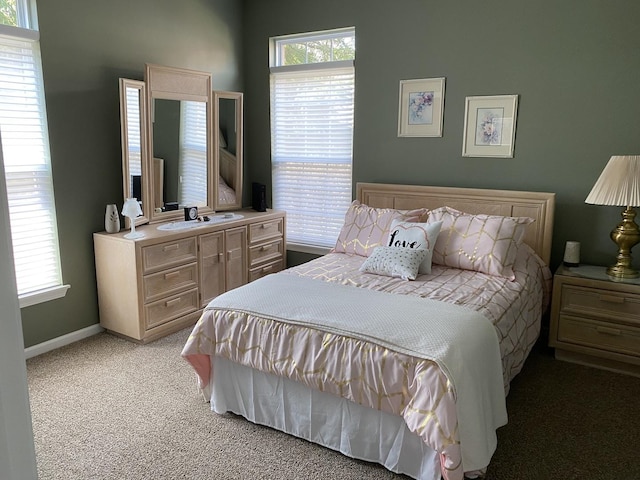 bedroom with baseboards, light colored carpet, and multiple windows