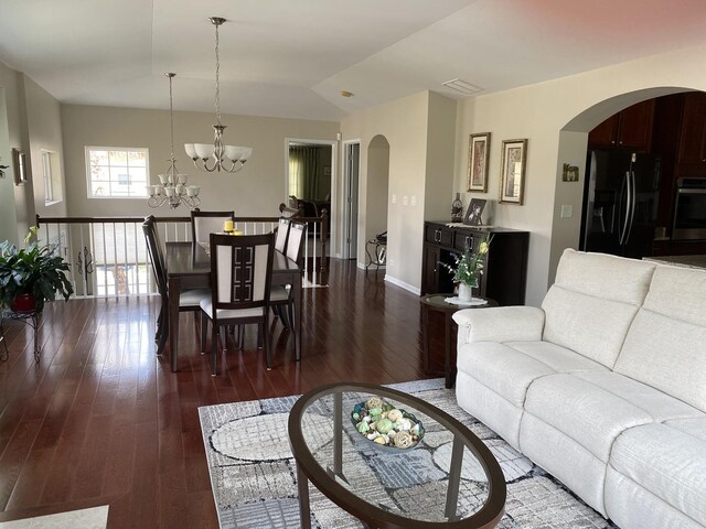 living room with an inviting chandelier, baseboards, arched walkways, and dark wood finished floors
