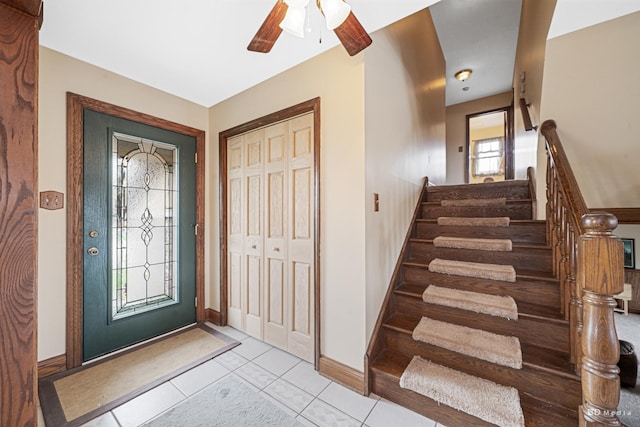 entrance foyer with stairway, baseboards, ceiling fan, and light tile patterned flooring