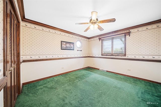 spare room featuring a ceiling fan, visible vents, carpet floors, baseboards, and ornamental molding
