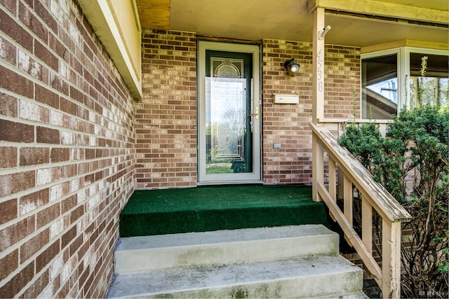 view of exterior entry with brick siding and a porch