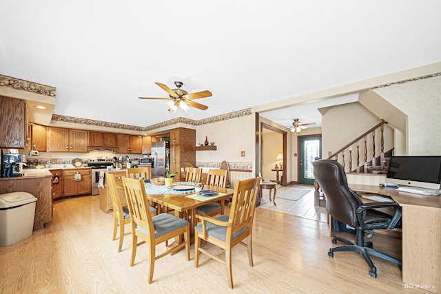 dining area with a ceiling fan, stairway, and light wood finished floors