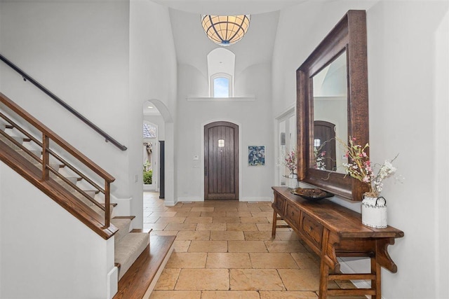 1784 Reserve Ct, Highland Park, IL 60035 - entrance foyer featuring a high ceiling, stone tile flooring, arched walkways, baseboards, and stairs