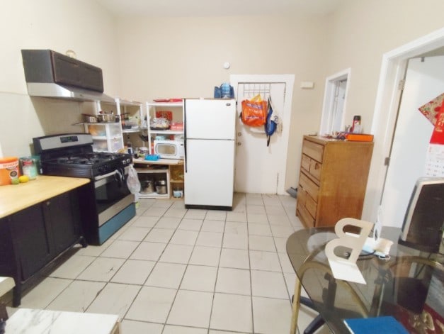 2919 S Quinn St, Chicago, IL 60608 - kitchen with light tile patterned flooring, gas range, light countertops, under cabinet range hood, and freestanding refrigerator