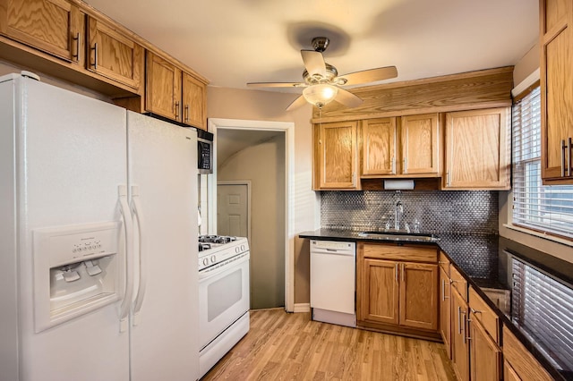 kitchen featuring light wood finished floors, a sink, backsplash, a ceiling fan, and white appliances