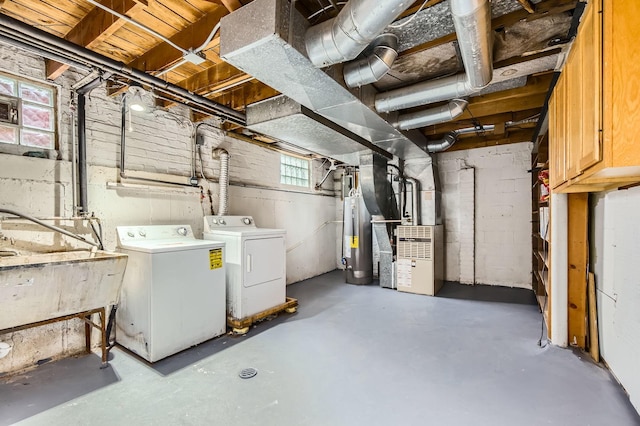 basement with heating unit, water heater, washer and dryer, and a sink