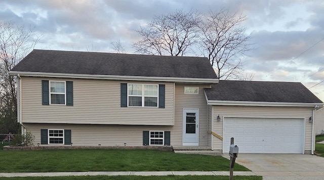 tri-level home with an attached garage, driveway, roof with shingles, and a front yard