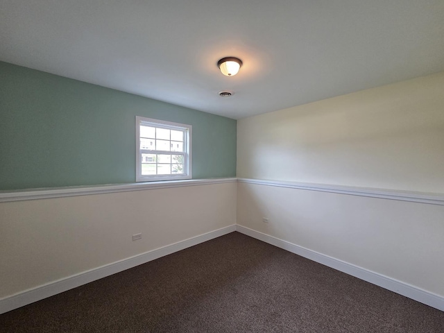 unfurnished room with visible vents, baseboards, and dark carpet