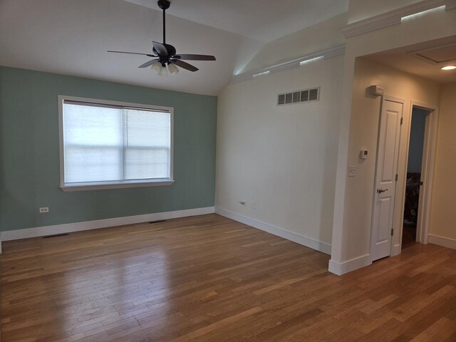 spare room featuring a ceiling fan, wood finished floors, baseboards, lofted ceiling, and visible vents