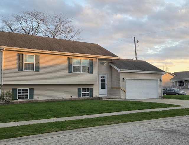 split level home featuring a garage, a yard, and driveway