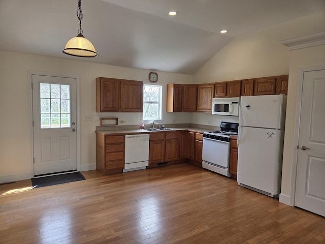 kitchen featuring vaulted ceiling, light wood finished floors, a sink, and white appliances