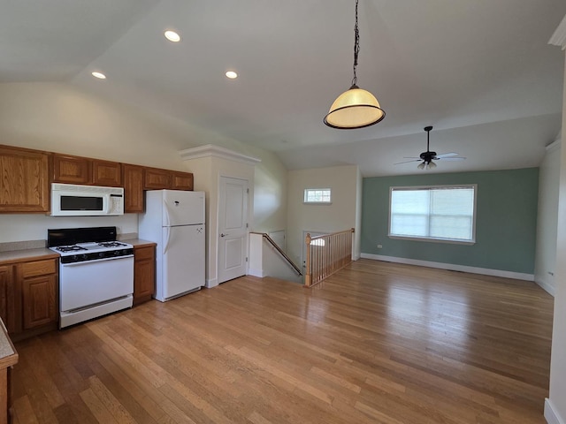 kitchen featuring brown cabinets, vaulted ceiling, light wood-type flooring, and white appliances