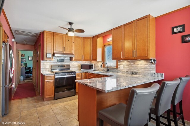 7046 W 63rd Pl, Chicago, IL 60638 - kitchen featuring a sink, backsplash, brown cabinetry, under cabinet range hood, and appliances with stainless steel finishes