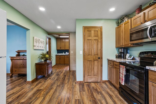 kitchen featuring dark wood-style flooring, stainless steel microwave, recessed lighting, and black range with electric stovetop