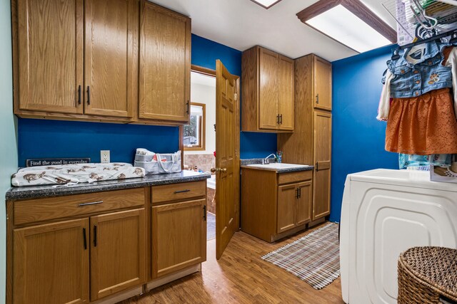 laundry area featuring washer / dryer, light wood-type flooring, and cabinet space