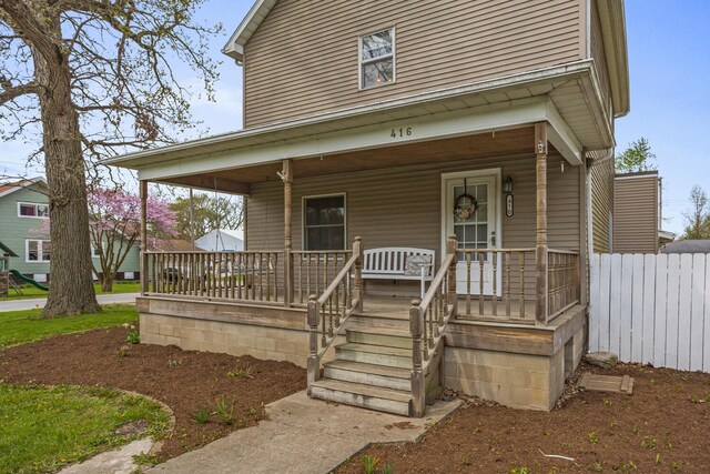 view of front of property featuring fence and a porch