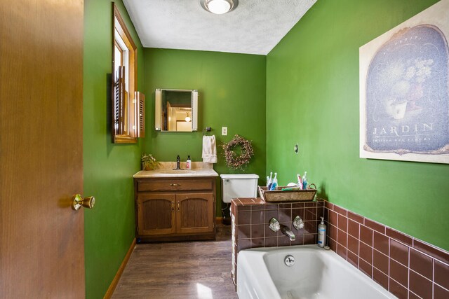 bathroom with a garden tub, wood finished floors, toilet, and vanity