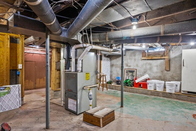 unfinished below grade area with freestanding refrigerator and heating unit
