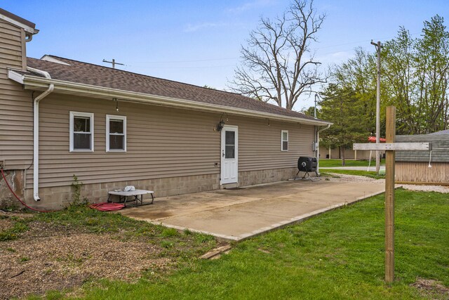 back of house with a patio, a shingled roof, and a yard