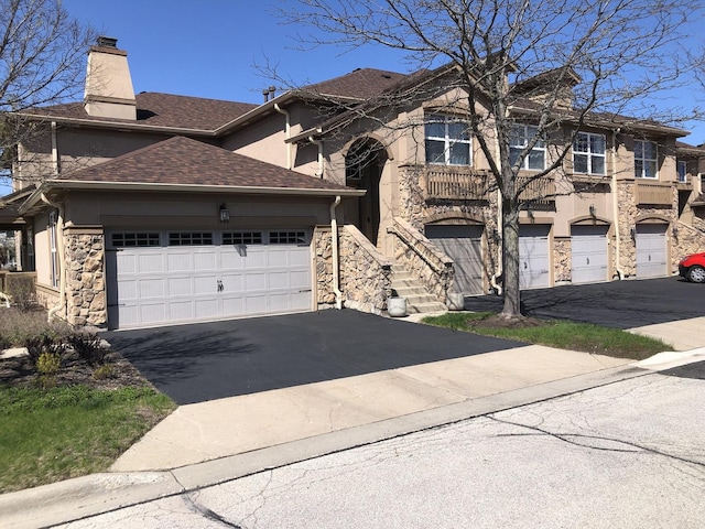 1952 Crenshaw Cir Unit 1952, Vernon Hills, IL 60061 - view of front facade with asphalt driveway, stone siding, a chimney, stucco siding, and roof with shingles