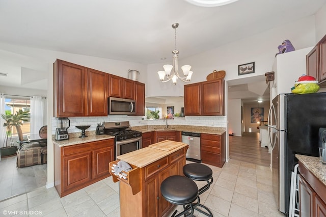 1952 Crenshaw Cir Unit 1952, Vernon Hills, IL 60061 - kitchen featuring appliances with stainless steel finishes, backsplash, a chandelier, hanging light fixtures, and a kitchen island