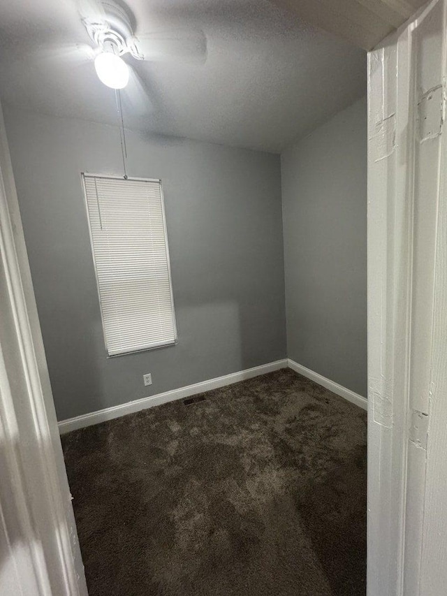 unfurnished room featuring dark colored carpet and baseboards
